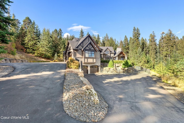 view of front of house featuring aphalt driveway, a garage, and stone siding