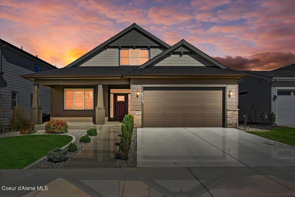 craftsman inspired home featuring stone siding, covered porch, driveway, and an attached garage