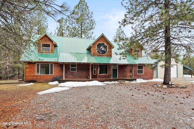 rustic home featuring a porch, a garage, an outdoor structure, and metal roof