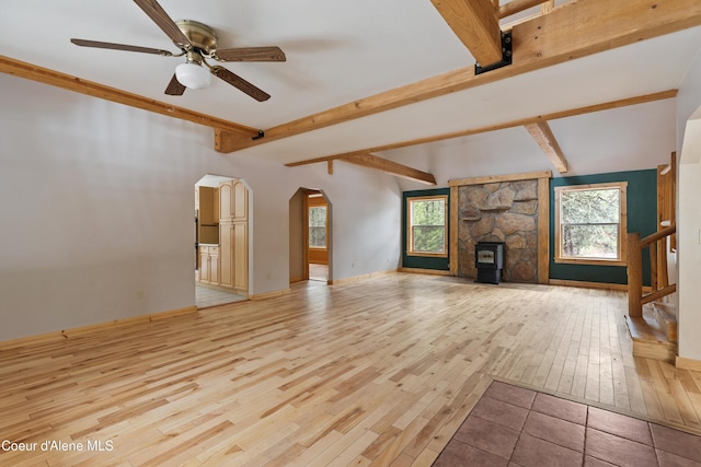 unfurnished living room with hardwood / wood-style flooring, beamed ceiling, a ceiling fan, and arched walkways