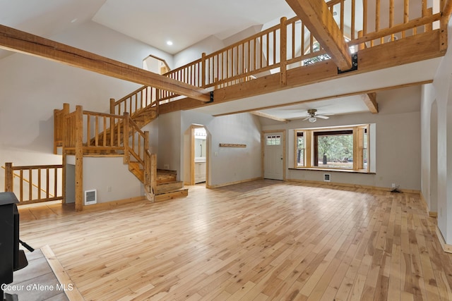 unfurnished living room featuring visible vents, baseboards, ceiling fan, a towering ceiling, and hardwood / wood-style flooring