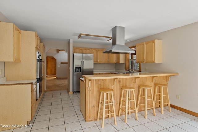 kitchen with light brown cabinets, a sink, stainless steel appliances, a peninsula, and island range hood