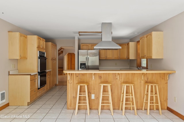 kitchen featuring light brown cabinets, a peninsula, stainless steel fridge with ice dispenser, double oven, and island range hood