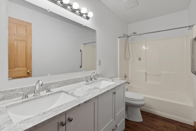 bathroom featuring shower / washtub combination, toilet, wood finished floors, and a sink