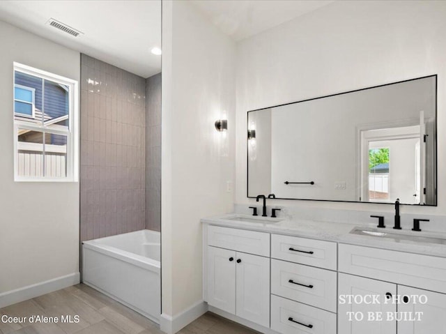 bathroom featuring a sink, visible vents, baseboards, and double vanity