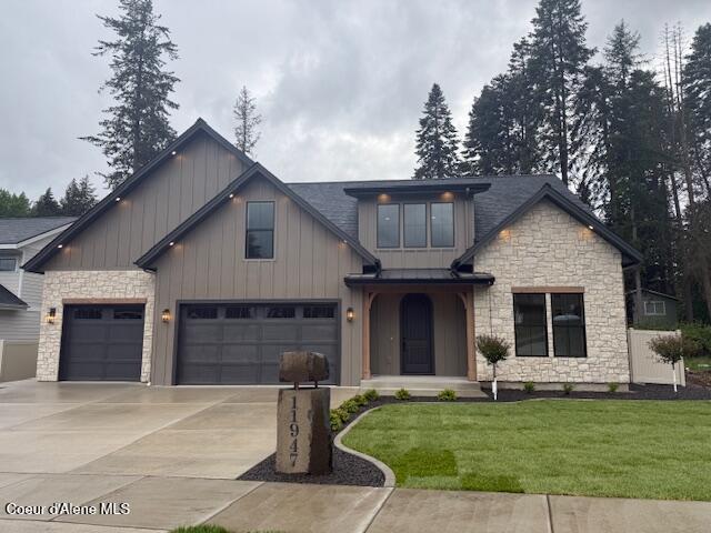 view of front of property featuring stone siding, board and batten siding, concrete driveway, a front lawn, and a garage