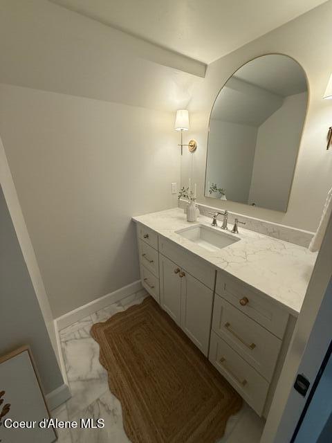 bathroom with marble finish flooring, vanity, and baseboards