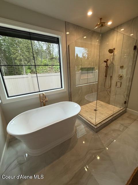 bathroom featuring marble tiled flooring, baseboards, a stall shower, a freestanding bath, and recessed lighting