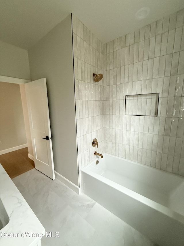 bathroom featuring marble finish floors, bathing tub / shower combination, and baseboards