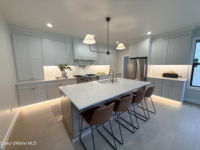 kitchen with a sink, high end appliances, recessed lighting, decorative backsplash, and custom range hood