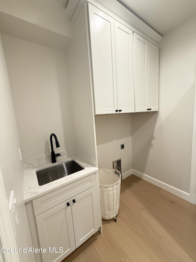 washroom with cabinet space, light wood-type flooring, hookup for an electric dryer, and baseboards