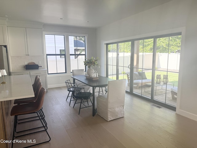 dining space with baseboards, light wood finished floors, and recessed lighting