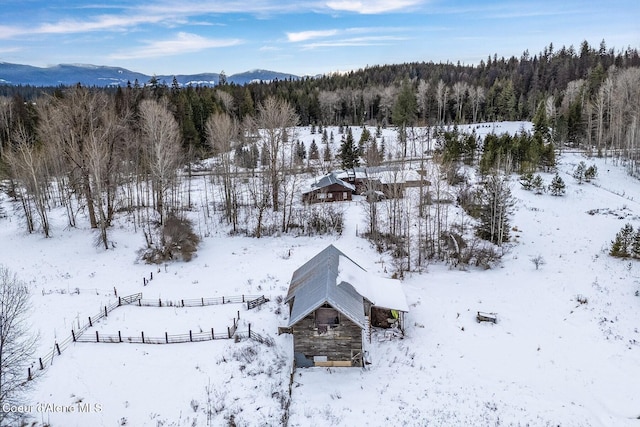 snowy aerial view with a mountain view and a wooded view