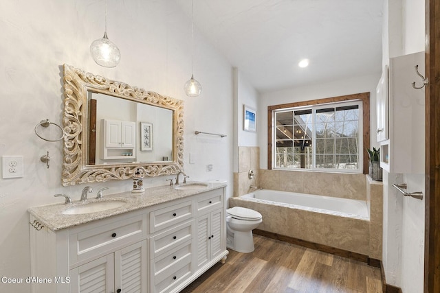 full bathroom with a sink, a garden tub, wood finished floors, and double vanity