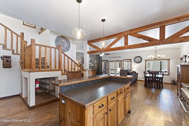 kitchen with open floor plan, dark countertops, wood finished floors, and vaulted ceiling with beams