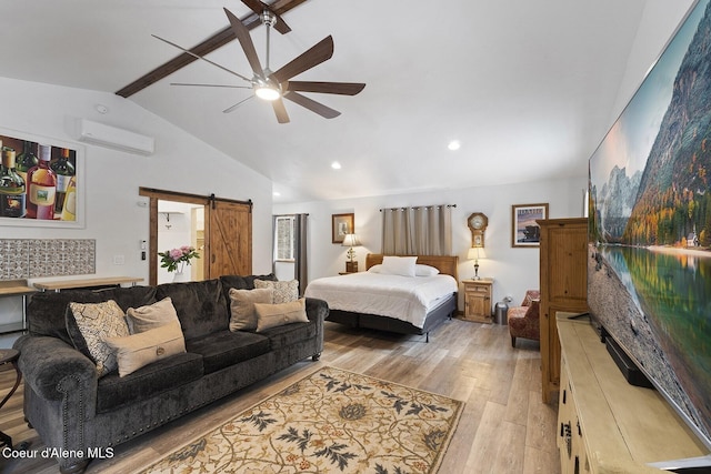 bedroom with a ceiling fan, light wood-style flooring, an AC wall unit, a barn door, and beamed ceiling