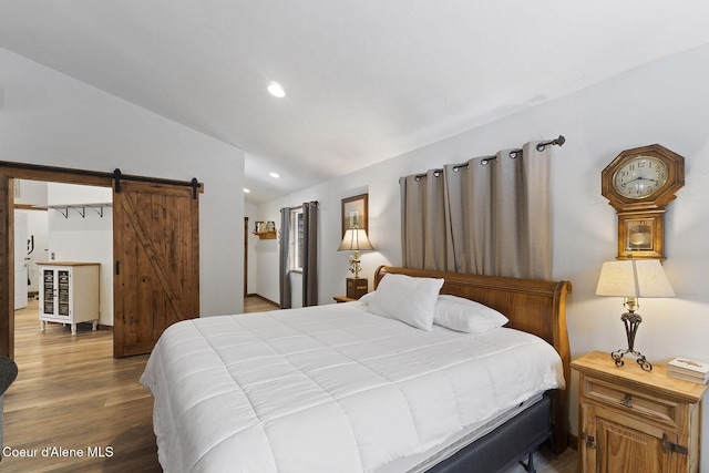 bedroom with recessed lighting, a barn door, lofted ceiling, and wood finished floors