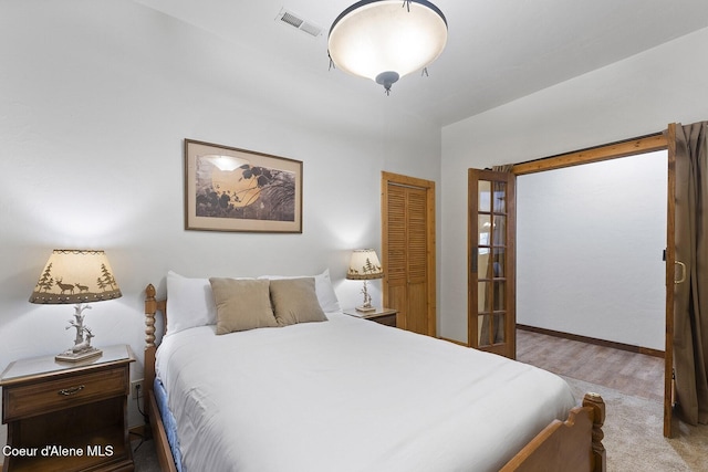 bedroom featuring wood finished floors, visible vents, a closet, and baseboards