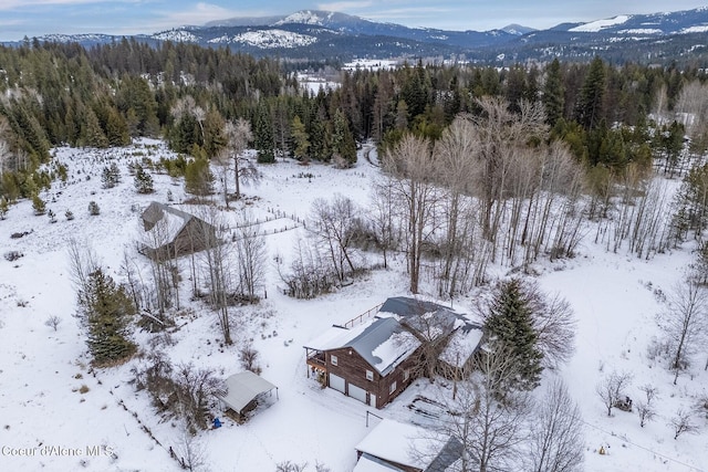 snowy aerial view with a mountain view and a forest view