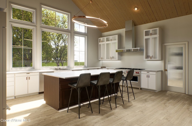 kitchen featuring a kitchen island, wall chimney range hood, light countertops, high end stainless steel range oven, and plenty of natural light