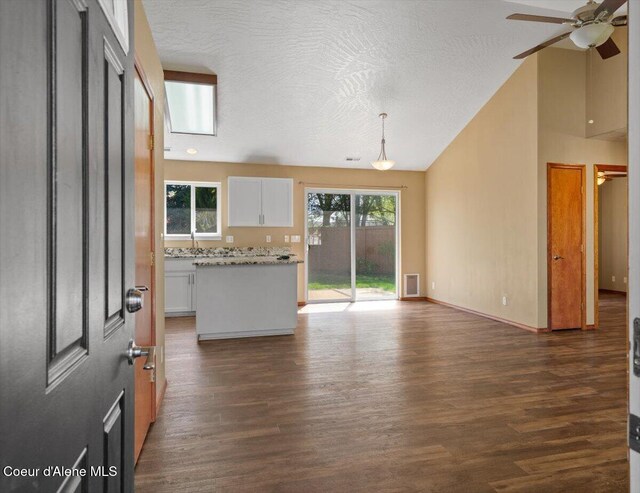 8920 N Torrey Ln, Hayden, ID 83835 - unfurnished living room featuring ceiling fan, a textured ceiling, baseboards, dark wood-type flooring, and visible vents
