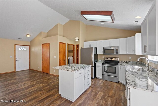 8920 N Torrey Ln, Hayden, ID 83835 - kitchen featuring a sink, stainless steel appliances, washer / dryer, a kitchen island, and dark wood-style floors