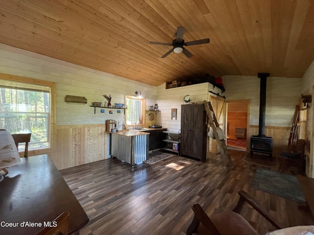1942 Two Tail Rd, Bonners Ferry, ID 83805 - living room with wood walls, vaulted ceiling, dark wood-style flooring, a wood stove, and ceiling fan
