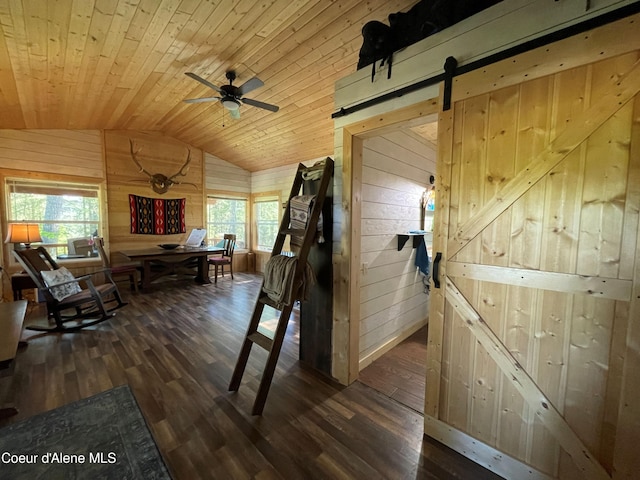 1942 Two Tail Rd, Bonners Ferry, ID 83805 - interior space featuring vaulted ceiling, wooden walls, a barn door, wood finished floors, and plenty of natural light