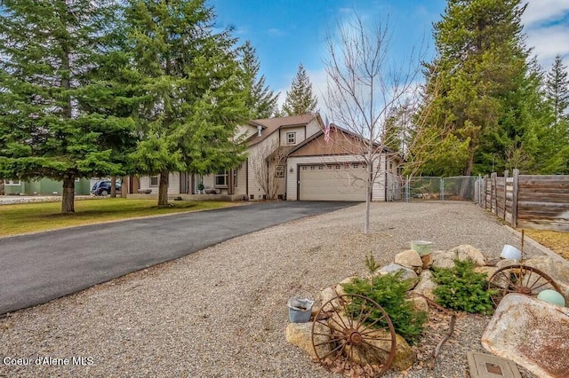 view of front of property featuring driveway, a garage, and fence