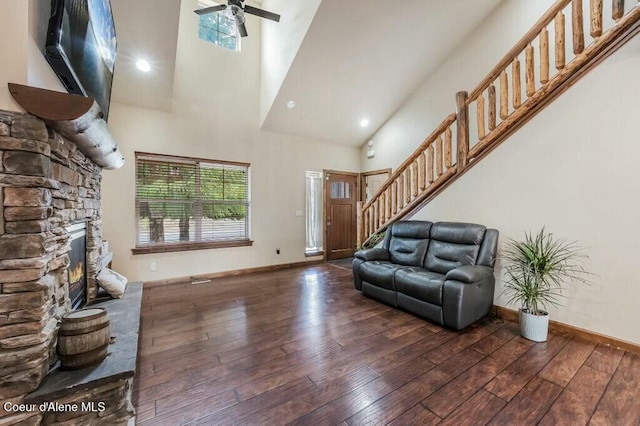 living room with stairs, hardwood / wood-style floors, baseboards, a high ceiling, and a ceiling fan