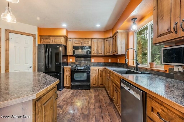 kitchen with a sink, dark wood-style flooring, black appliances, and dark countertops