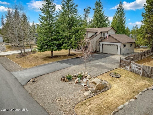 view of front of house featuring a garage, aphalt driveway, and fence