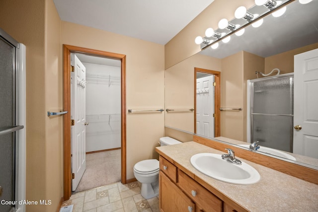 full bathroom featuring a stall shower, vanity, toilet, and a spacious closet