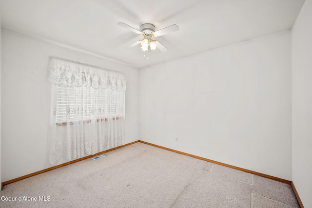 carpeted empty room with visible vents, baseboards, and ceiling fan