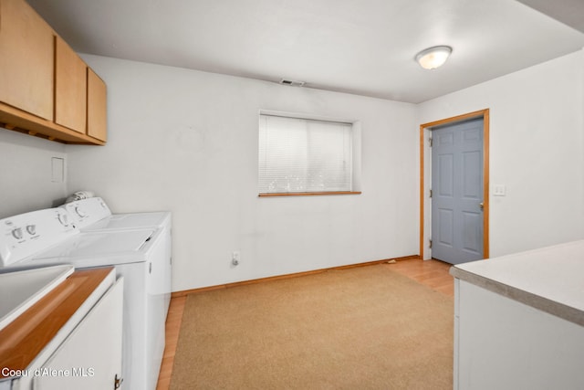 washroom featuring cabinet space, washing machine and dryer, baseboards, and light wood finished floors