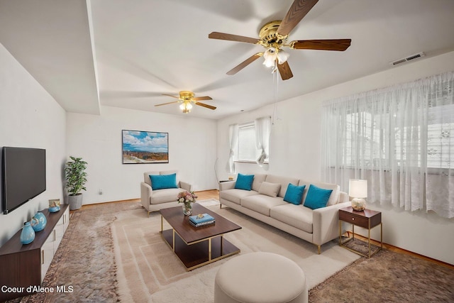 living room with visible vents, baseboards, and ceiling fan