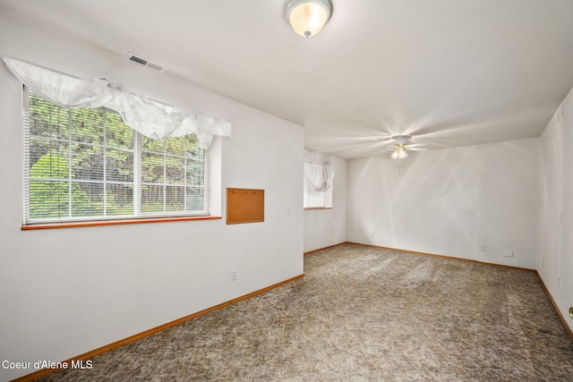 carpeted empty room with baseboards, visible vents, and a ceiling fan