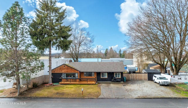 ranch-style home featuring a chimney, a deck, a front lawn, and fence