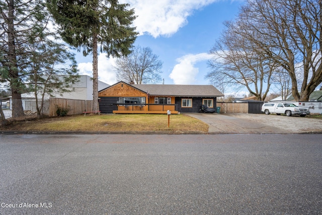 view of front of house with a front lawn, concrete driveway, a deck, and fence