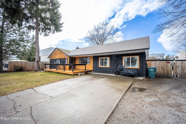 view of front of house featuring fence, a wooden deck, a chimney, a front lawn, and concrete driveway