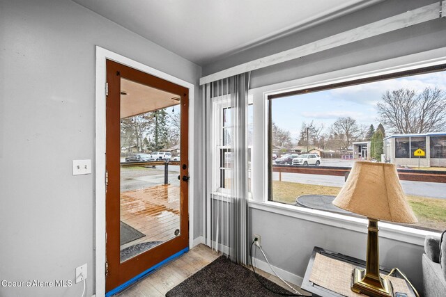 doorway with baseboards and wood finished floors