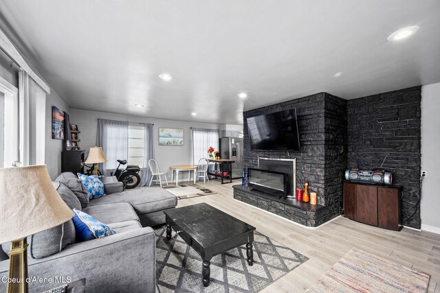 living room featuring recessed lighting, a fireplace, baseboards, and wood finished floors