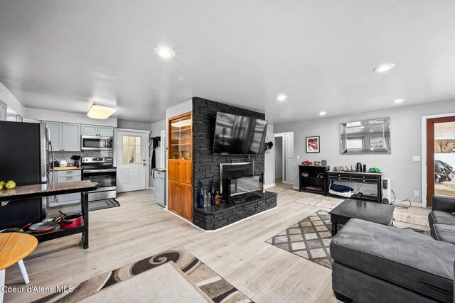living area with a fireplace, recessed lighting, light wood-type flooring, and baseboards