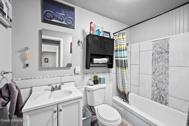 bathroom with shower / tub combo, toilet, tile walls, and vanity