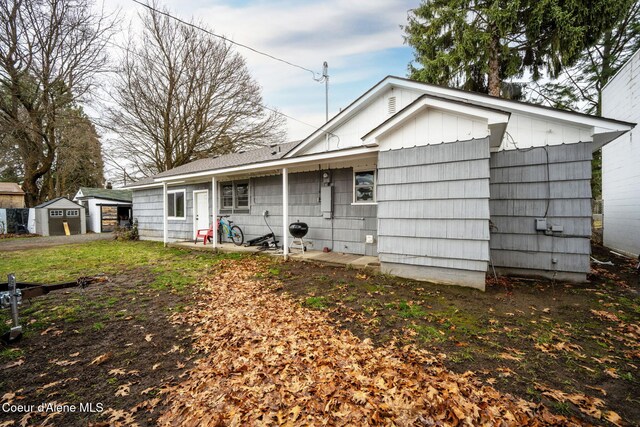 back of property featuring an outdoor structure and a storage unit