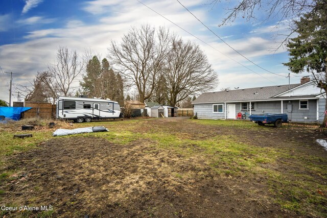 view of yard with an outbuilding, a storage unit, and fence