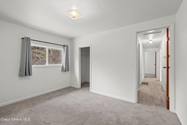 unfurnished bedroom featuring carpet, baseboards, a closet, and a textured ceiling