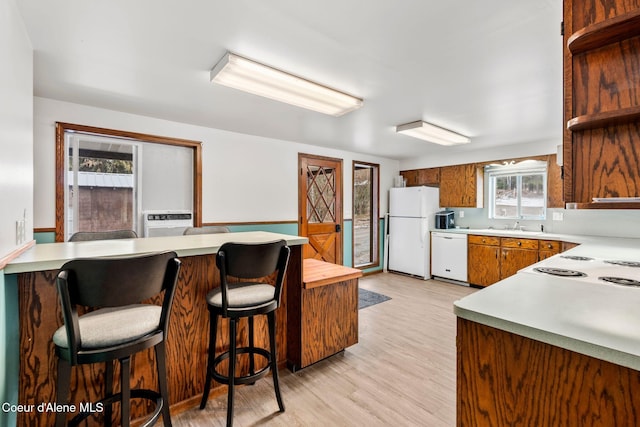 kitchen with white appliances, light wood-style flooring, brown cabinetry, and light countertops