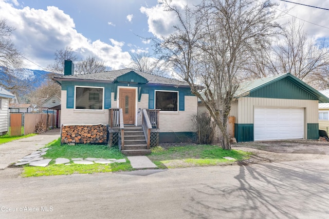 bungalow-style home with dirt driveway, fence, a garage, and a chimney