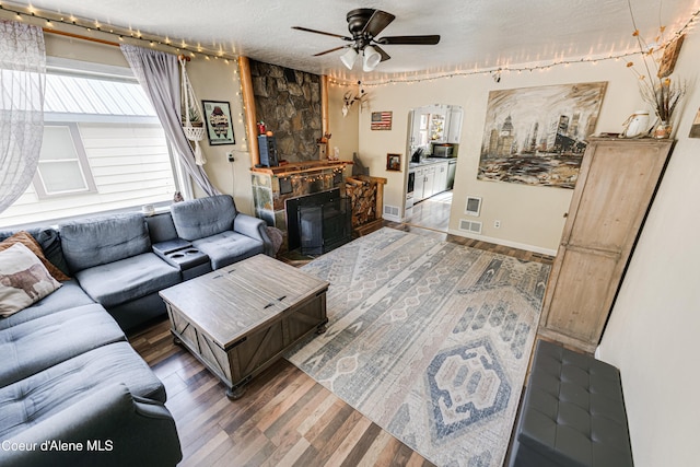 living room featuring a fireplace, a ceiling fan, and wood finished floors